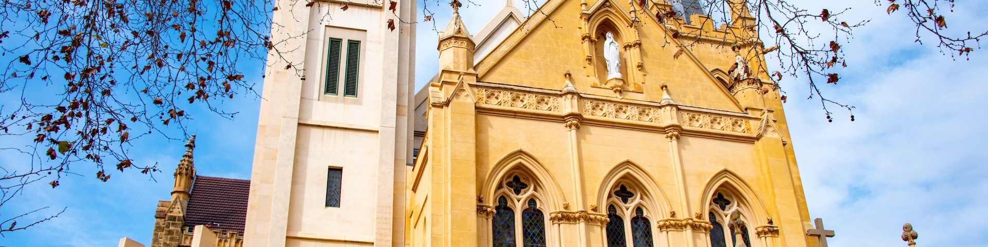 Uma igreja histórica com uma alta torre de sino e vitrais elaborados.
