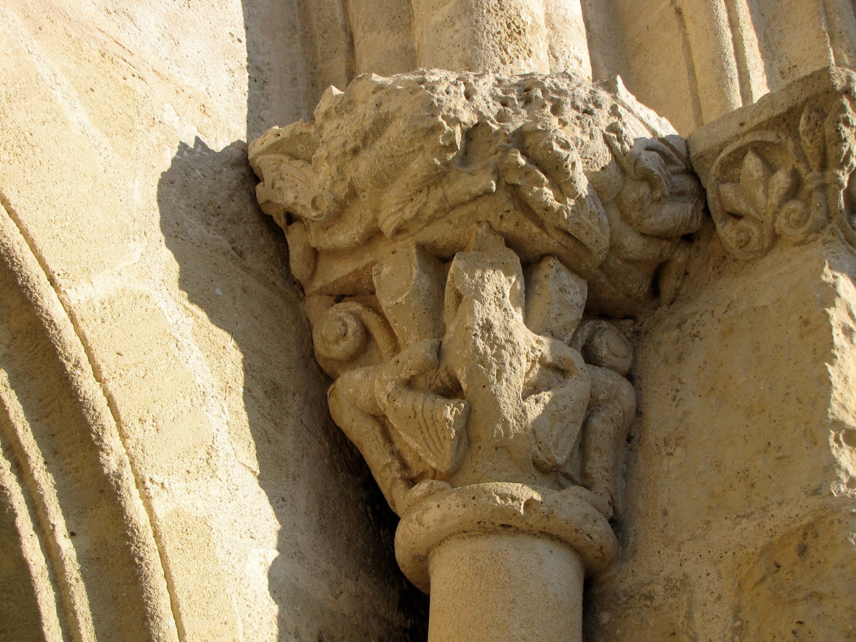 A detailed stone carving of a mythical creature with wings and a serpentine body, set against a textured stone background.