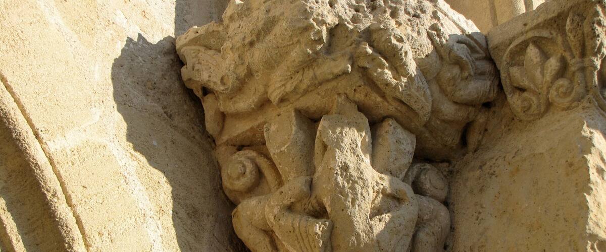 A detailed stone carving of a mythical creature with wings and a serpentine body, set against a textured stone background.