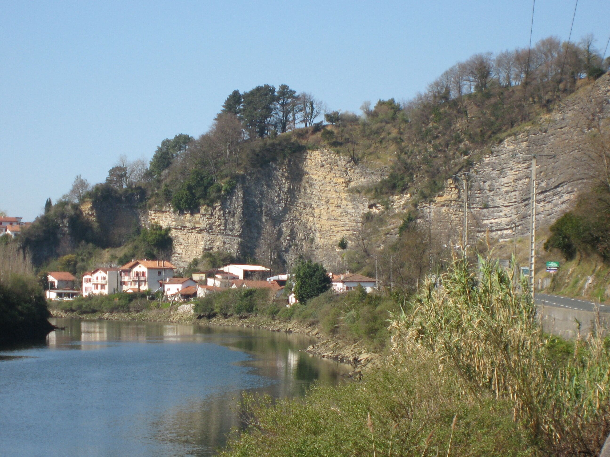 La Bidassoa et le village de Biriatou. Vue vers l'aval et vers l'ouest depuis la D811 près de la redoute Louis XIV. L'Espagne est à gauche (en rive gauche). Le pont de Béhobie, sur la commune d'Urrugne, est à environ 500 m devant nous, après le coude de la rivière.
