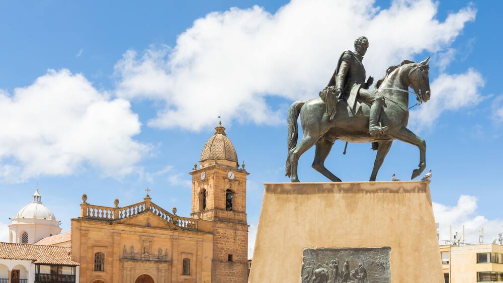 A statue of a man on a horse in front of a historic building with a clock tower.