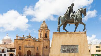 Estátua de um homem montado em cavalo em frente a um edifício histórico com torre do relógio.