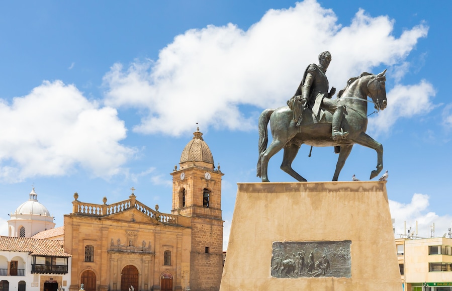 A statue of a man on a horse in front of a historic building with a clock tower.