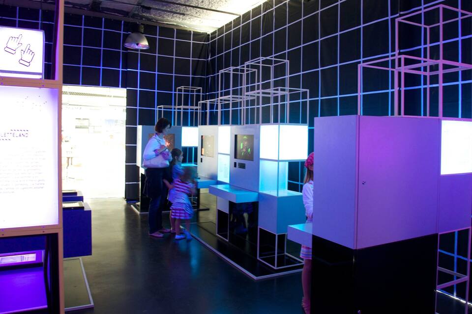 An indoor exhibition with illuminated cube structures and a display table.