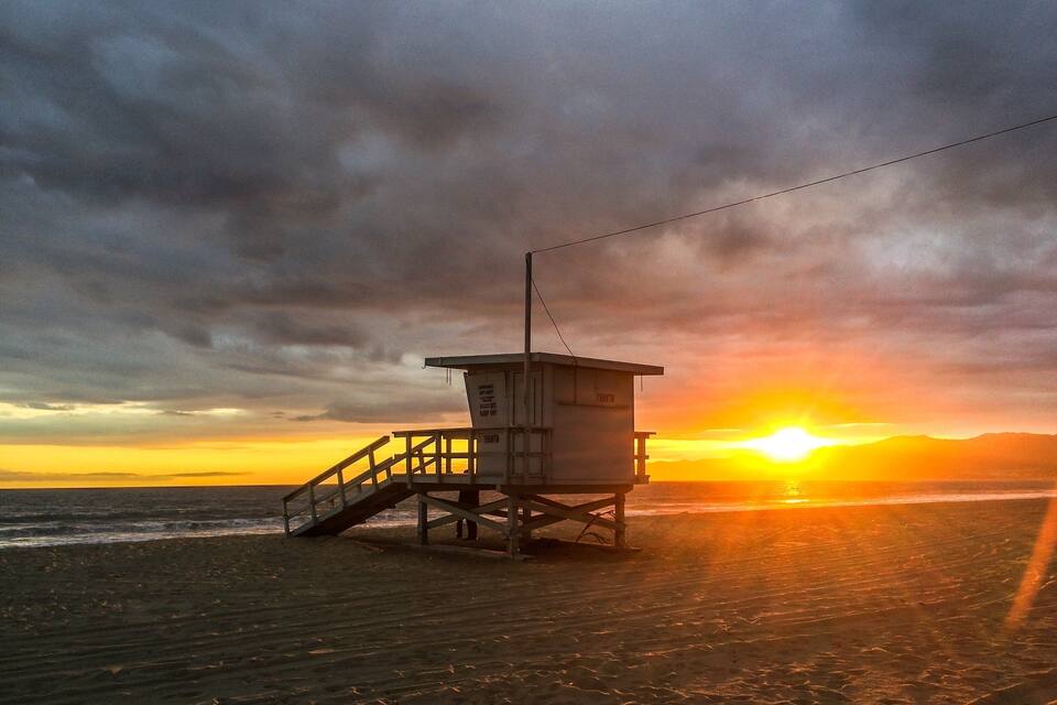 Una torre de salvavidas en una playa al atardecer.