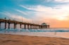 Manhattan beach pier at sunset, orange-pink sky with bright colors, beautiful landscape with ocean and sand