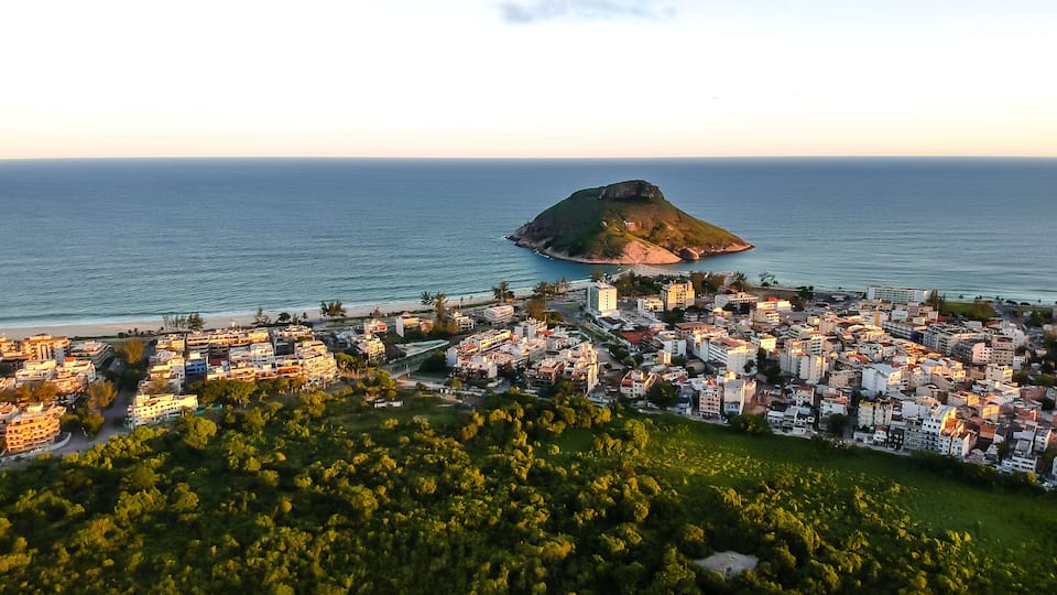 Paisagem costeira com uma colina imponente e uma praia.