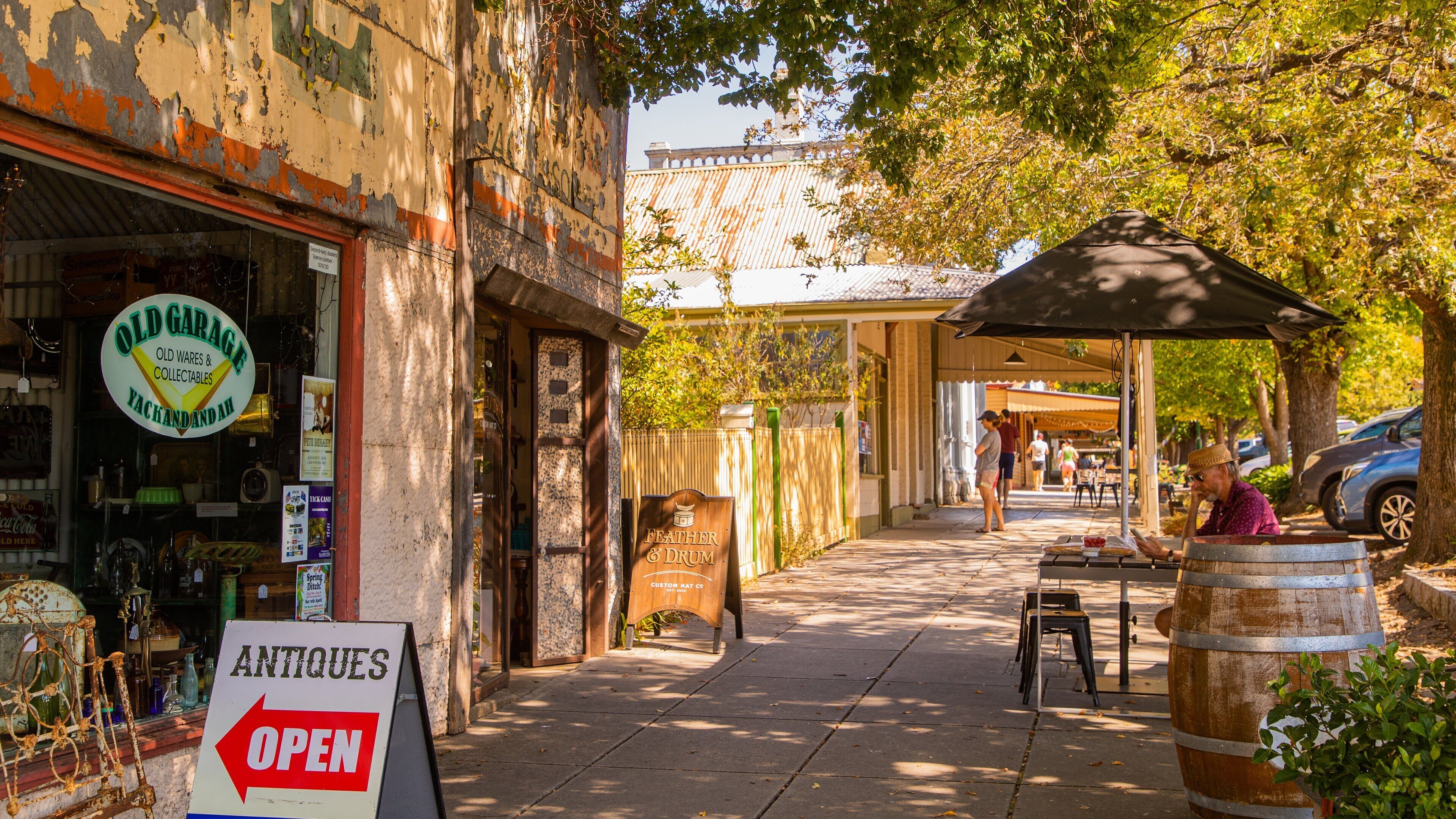 A street with antique shops, a sign for 'Old Garage' and 'Antiques Open', and a wooden barrel.
