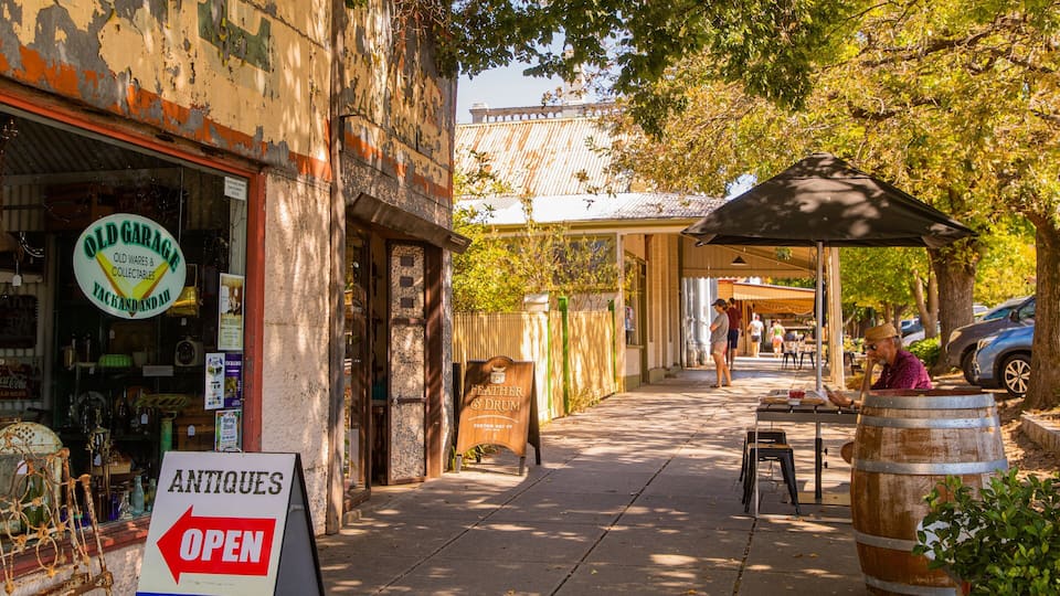 A street with antique shops, a sign for 'Old Garage' and 'Antiques Open', and a wooden barrel.