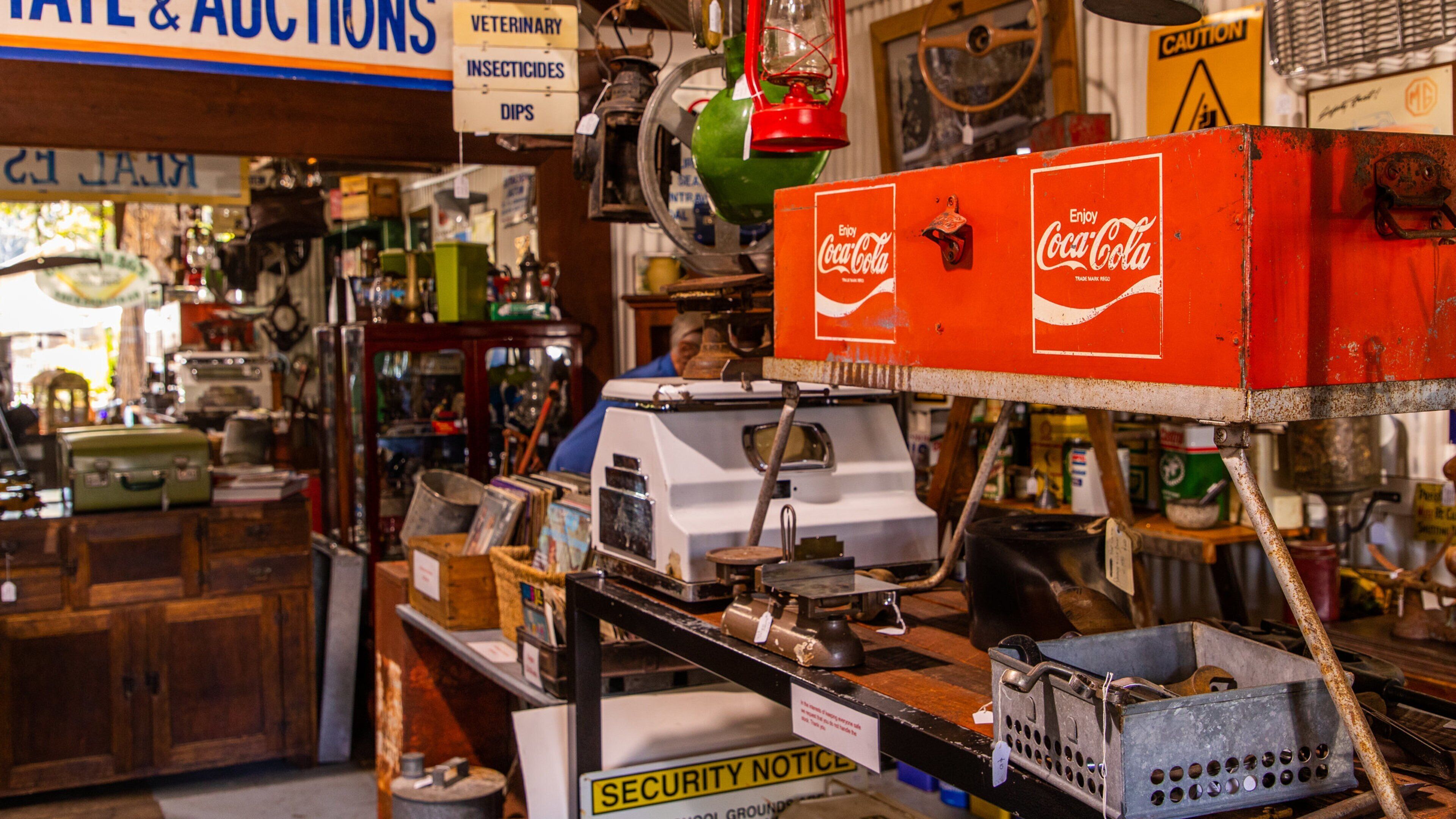 Una tienda de antigüedades abarrotada con objetos antiguos y una máquina expendedora de Coca-Cola.