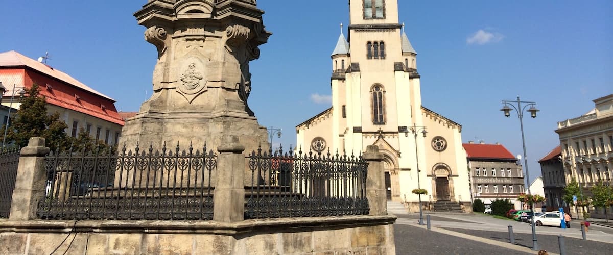 A historic monument with intricate sculptures and a church with a tall spire.