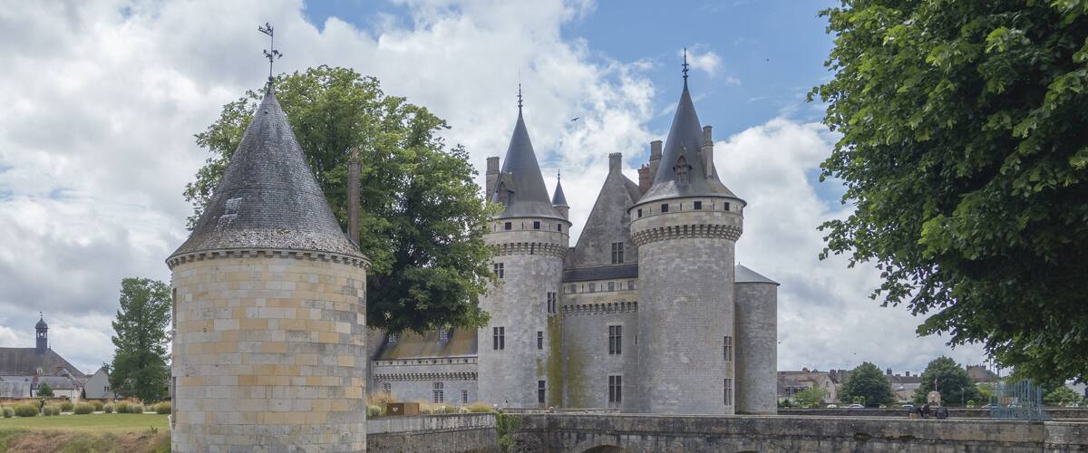 A historic castle with a moat, a bridge, and a tower.