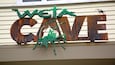 A metal sign with the words "Weta Cave" and a green insect sculpture.