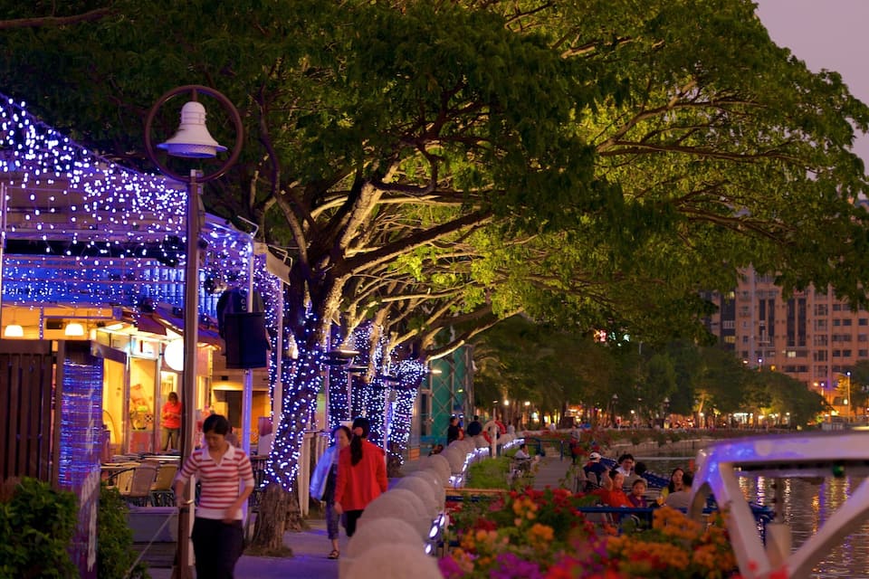 A riverside walkway adorned with blue lights and trees.
