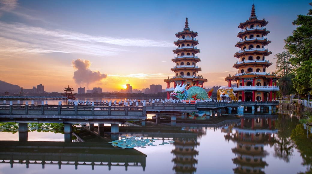 A multi-tiered pagoda, a calm lake reflecting the structure, and a bridge in the foreground.