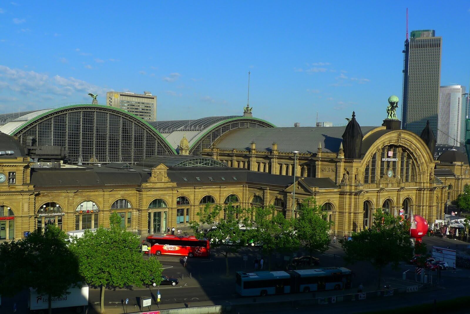 A historic train station with a large clock tower and a modern skyscraper in the background.