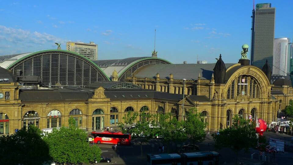 A historic train station with a large clock tower and a modern skyscraper in the background.