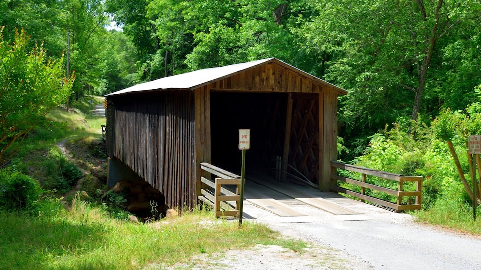 A wooden covered bridge with a 'No Parking' sign in front.