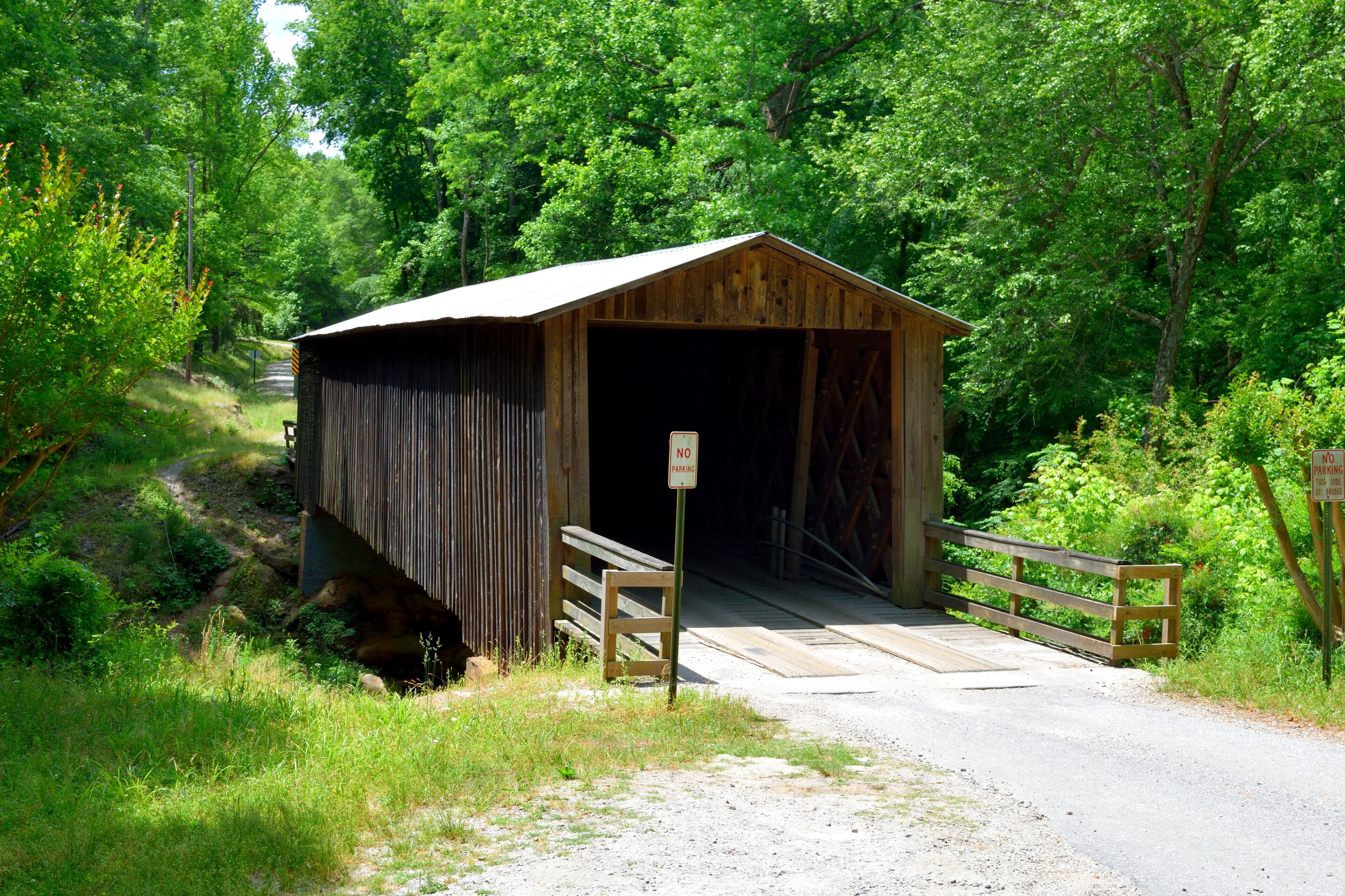 A wooden covered bridge with a 'No Parking' sign in front.