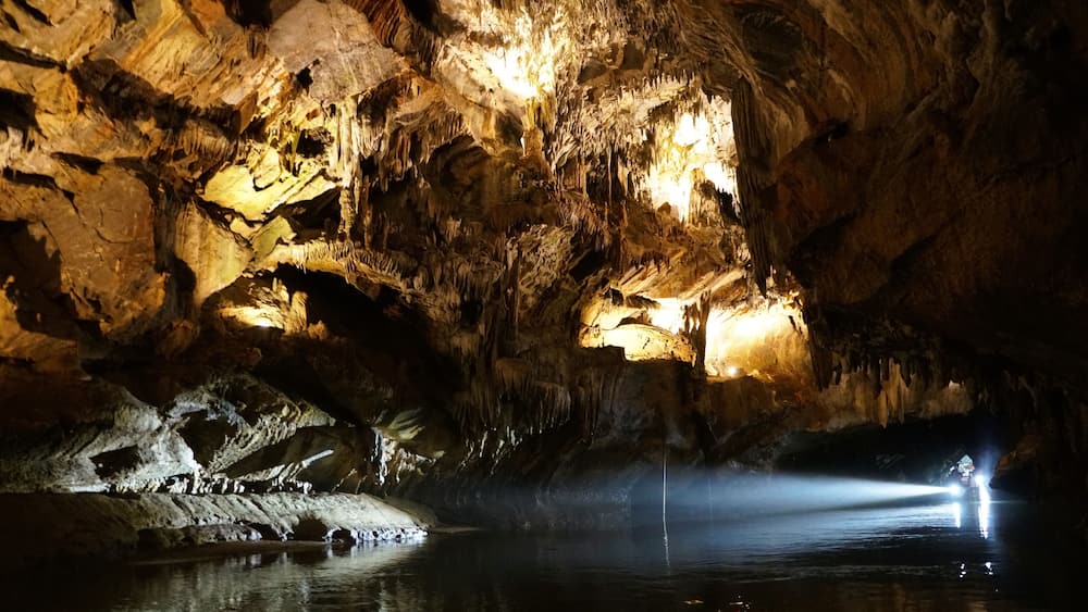 The boat light streams into Penn's Cave, illuminating the cave's intricate rock formations.