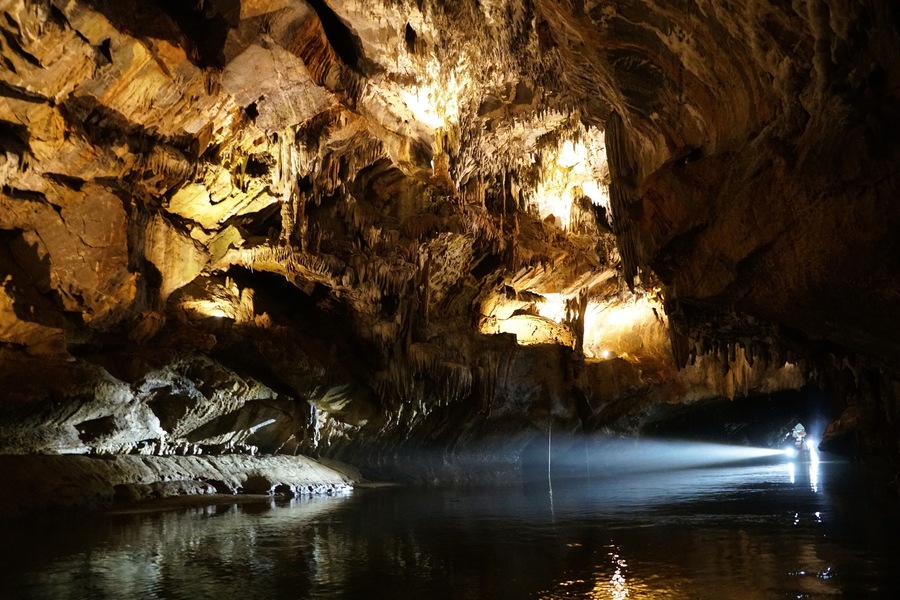 The boat light streams into Penn's Cave, illuminating the cave's intricate rock formations.