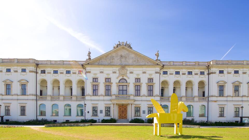 A classical building with a large yellow sculpture in front.