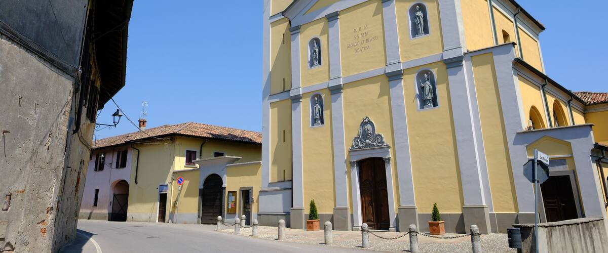 A yellow church with a bell tower and a clock.