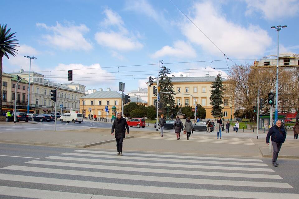 Un paso de cebra en una intersección urbana, con peatones, semáforos y edificios al fondo.