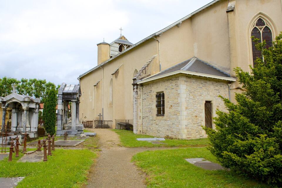 Une église dotée d’une façade en pierre, un petit bâtiment en pierre et une croix à l’entrée.