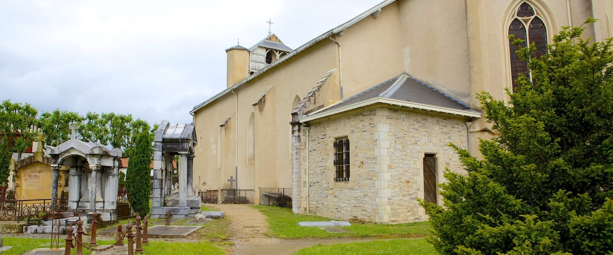 A church with a stone facade, a small stone building, and a cross at the entrance.