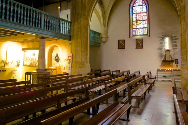 L’intérieur d’une église avec des bancs en bois, un vitrail et une galerie.