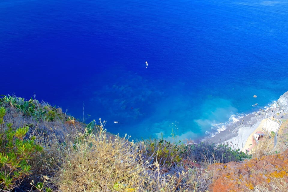 Un paisaje costero con aguas azul cristalino, acantilados rocosos y vegetación escasa.
