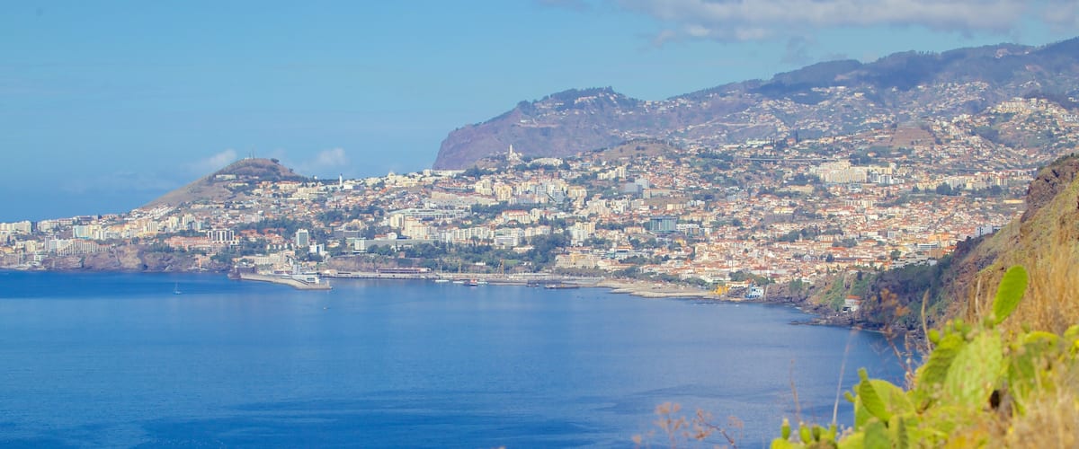 A coastal city with a mountain in the background and a clear blue sea.