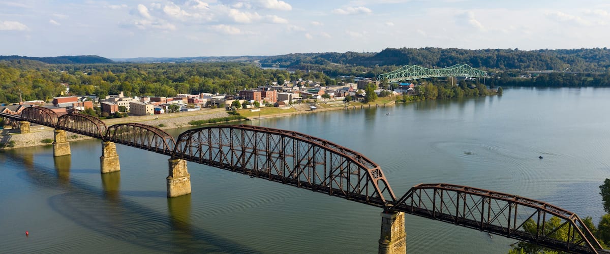 A steel bridge over a river with a town in the background.