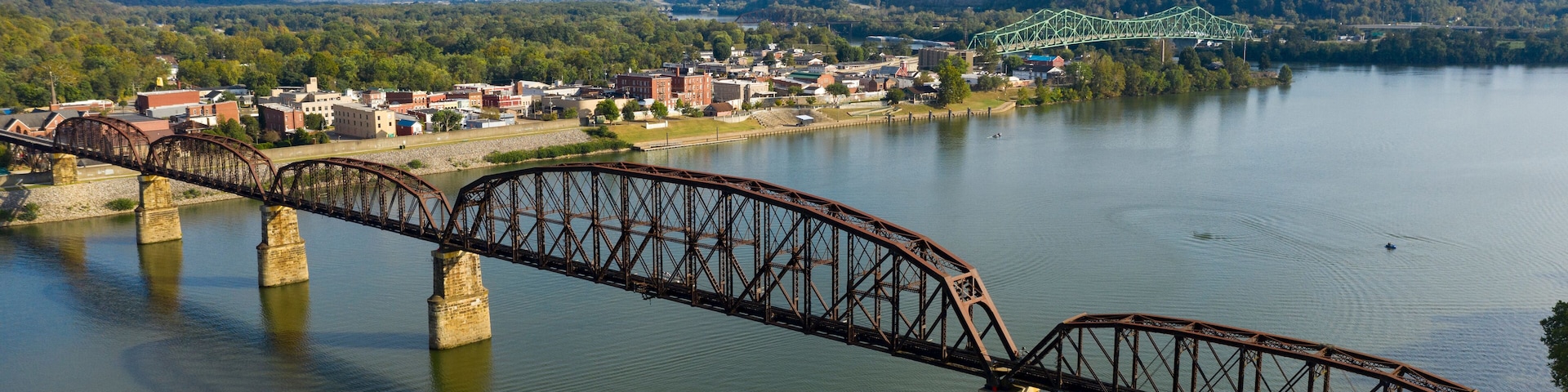 A steel bridge over a river with a town in the background.