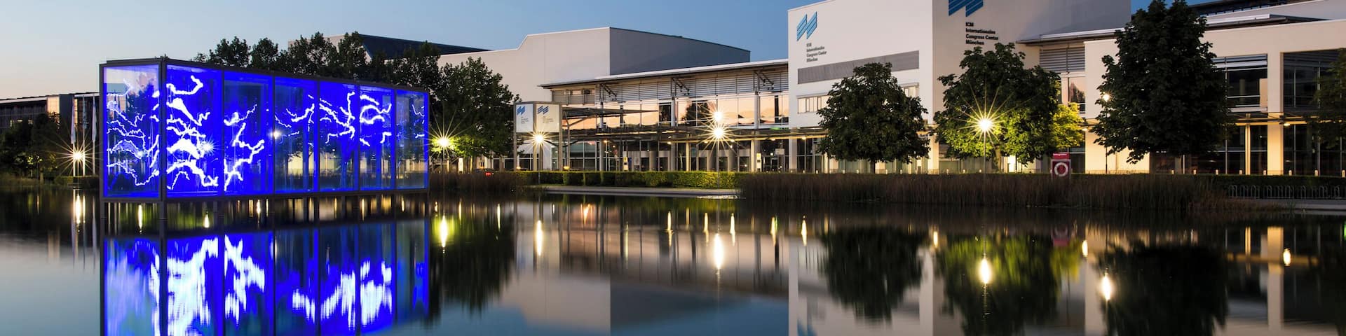 A modern building with a reflective water body in front.