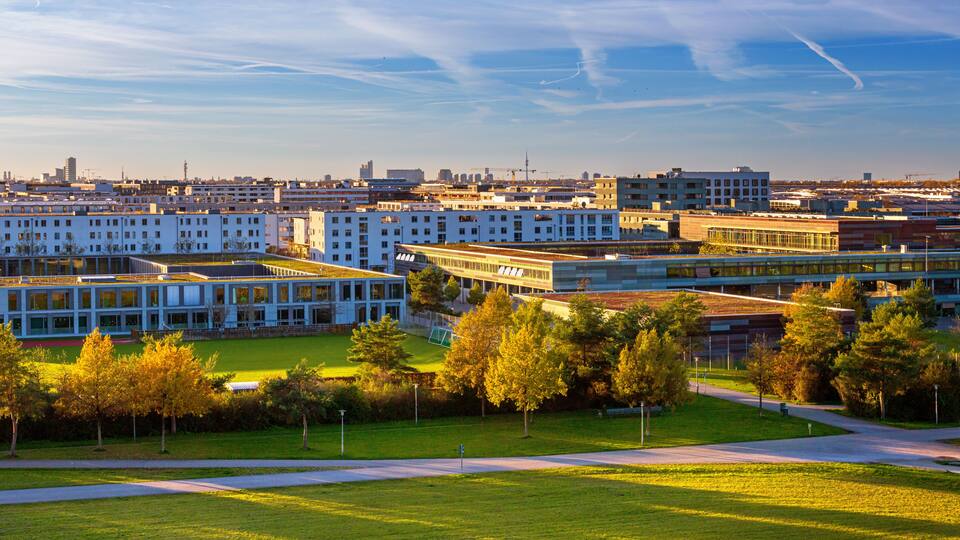 A modern urban campus with multiple buildings, green spaces, and a clear sky.