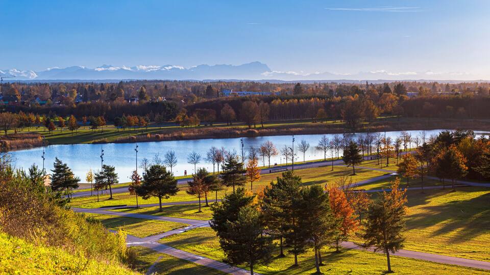 A lake surrounded by trees and a park with a clear sky.