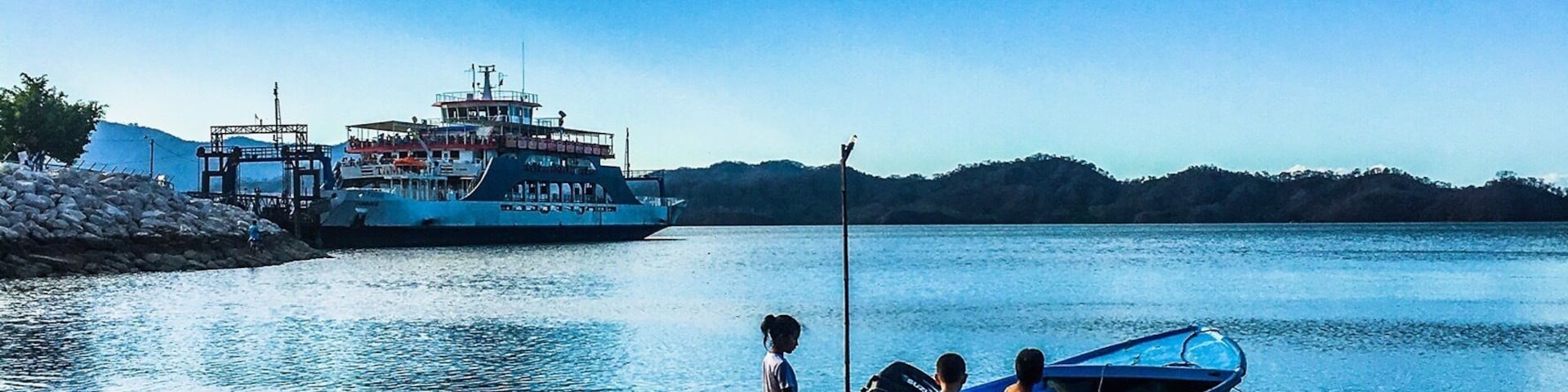 Costa Rican youth ready to take out their small boat with the big Paquera to Puntarenas ferry in the background #pacquera #puntarenas #ferry #costarica #nicoyapeninsula #boat #beach #ocean #puravida #lifeatexpedia