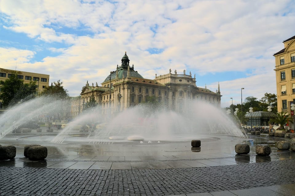 A historic building with a dome and a fountain in front.