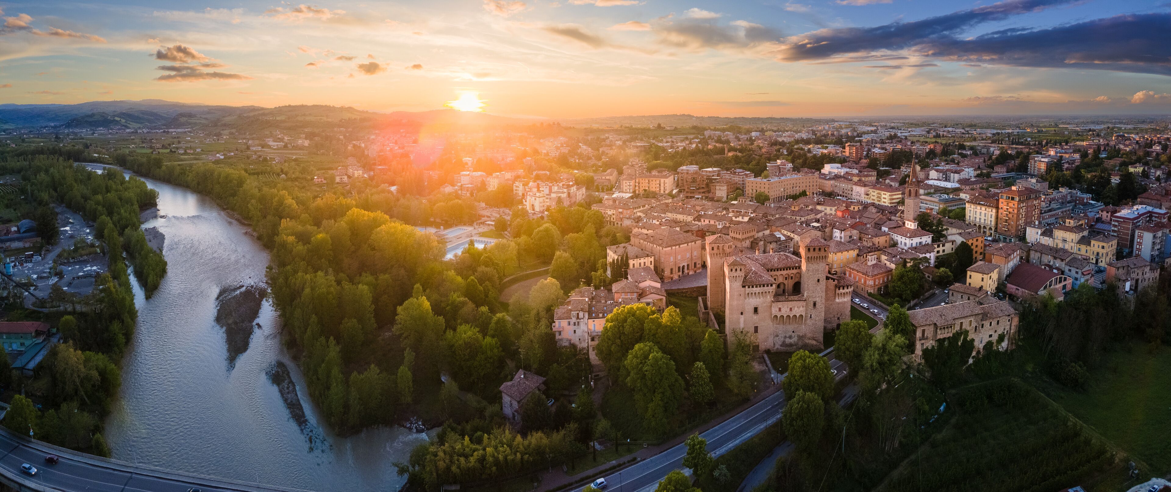 A river winding through a town with a prominent castle and surrounding greenery.