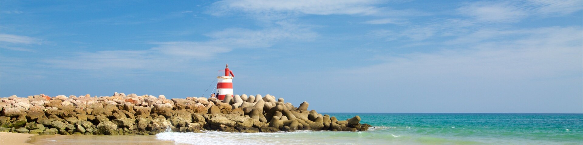 Ilha de Tavira Beach which includes a beach, general coastal views and rocky coastline