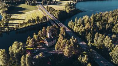 A bridge over a river, surrounded by fields and forests.