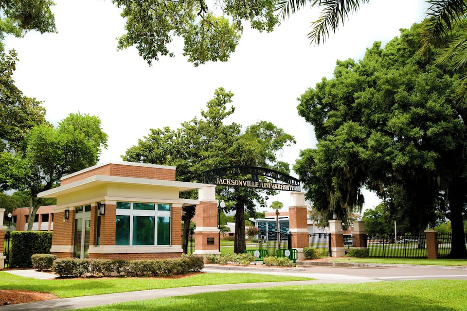 Un campus universitario con una entrada principal destacada, árboles verdes y un césped bien cuidado.