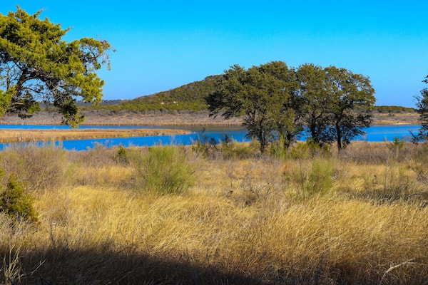 Stillhouse Hollow Lake landscape with trees, and a lush meadow at Dana Peak Park, Harker Heights Texas