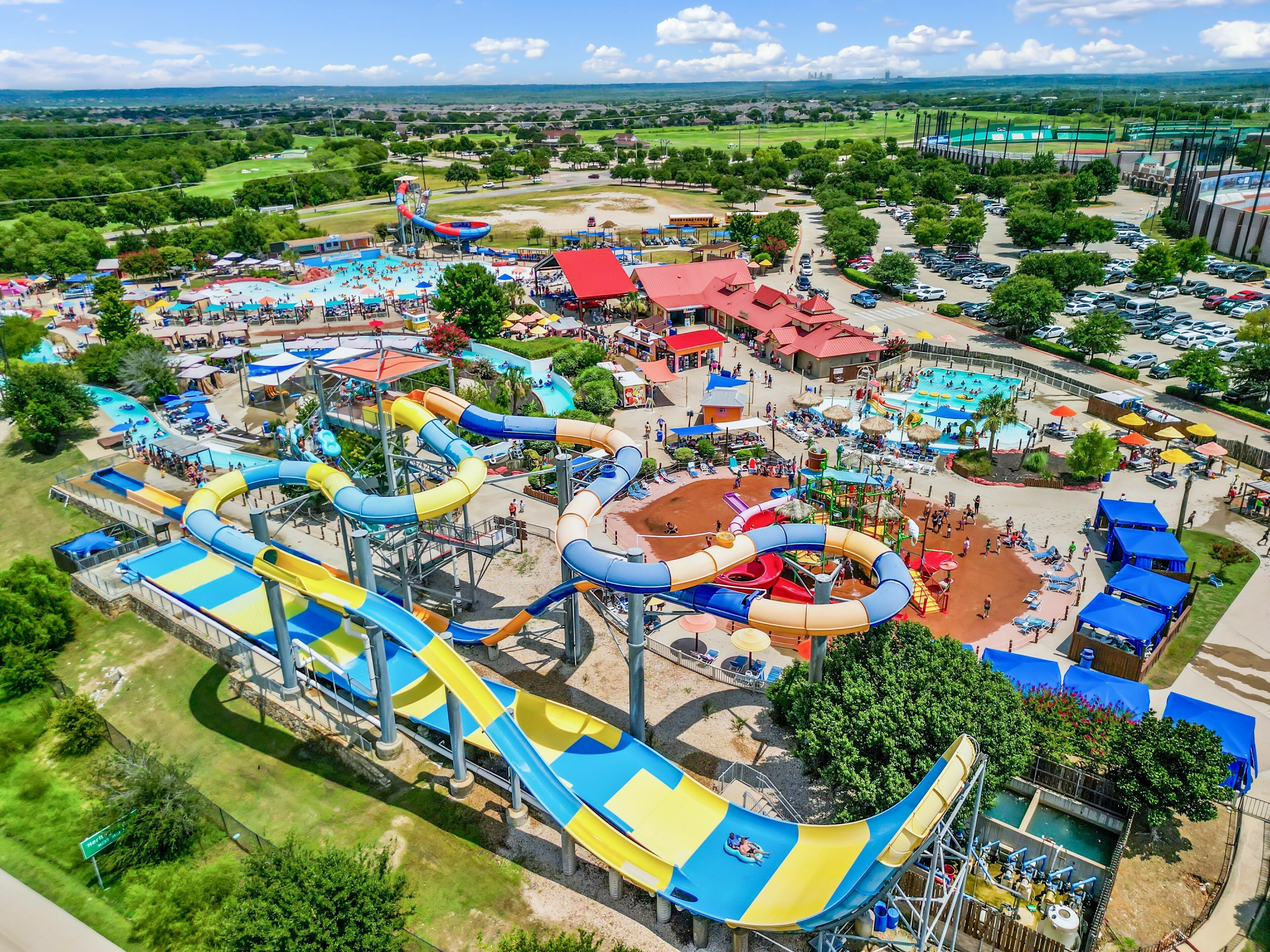 Aerial view of a busy water park with various slides, pools, and people enjoying summer activities