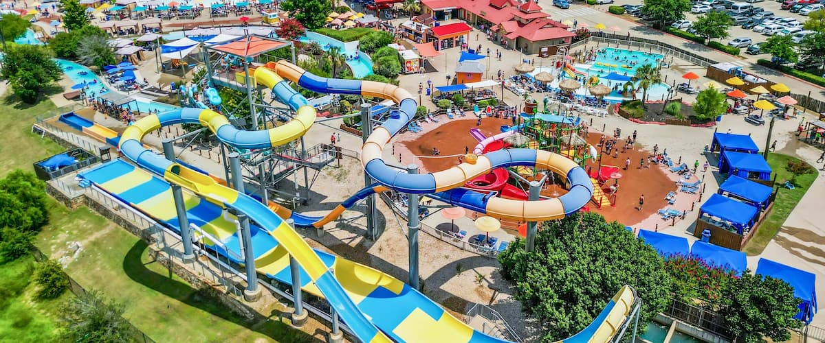 Aerial view of a busy water park with various slides, pools, and people enjoying summer activities
