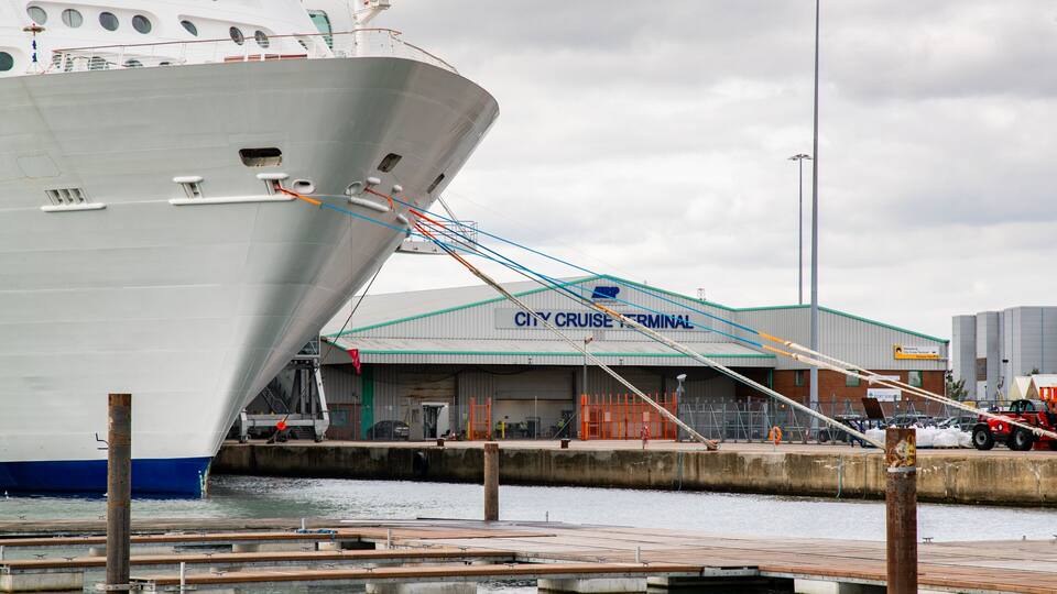 A large cruise ship docked at a port with a terminal labeled "City Cruise Terminal".