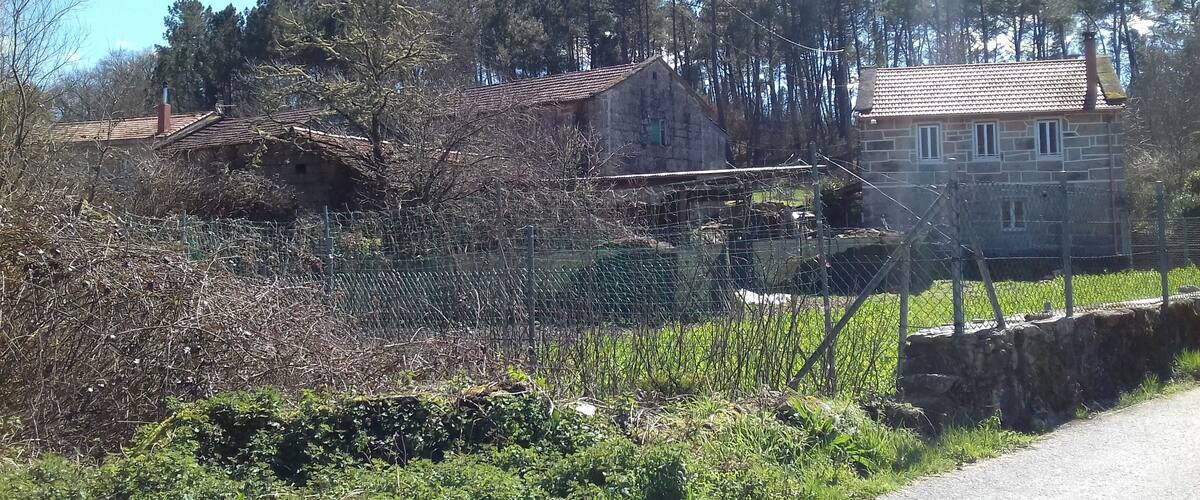 A rural landscape with stone houses, a wire fence, and a stone wall.
