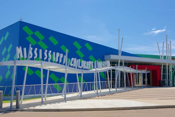 El exterior del Museo de los Niños de Mississippi, con una fachada azul y verde estampada y una entrada roja.